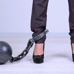 Business worker with ball and chain attached to foot