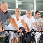 Happy senior citizens exercising in spinning class in fitness ce