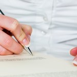 a woman signs a contract or a will with a fountain pen.