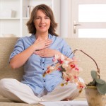 Woman practicing self Reiki transfering energy through palms, a