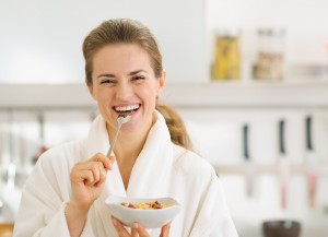 Smiling Young Woman In Bathrobe Eating Healthy Breakfast